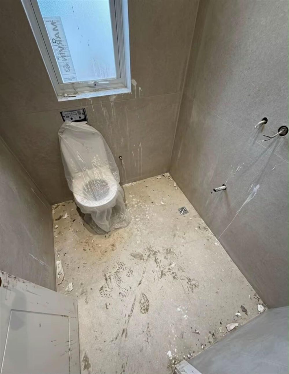 Bathroom with construction dust, paint stains and a dirty floor before cleaning