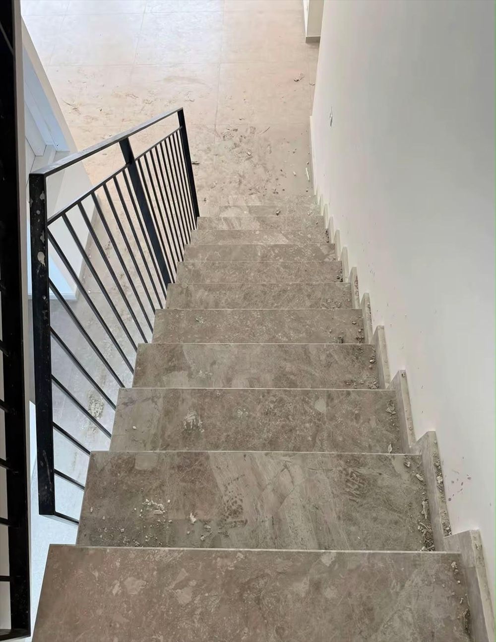 Marble staircase covered in renovation dust and construction debris before cleaning